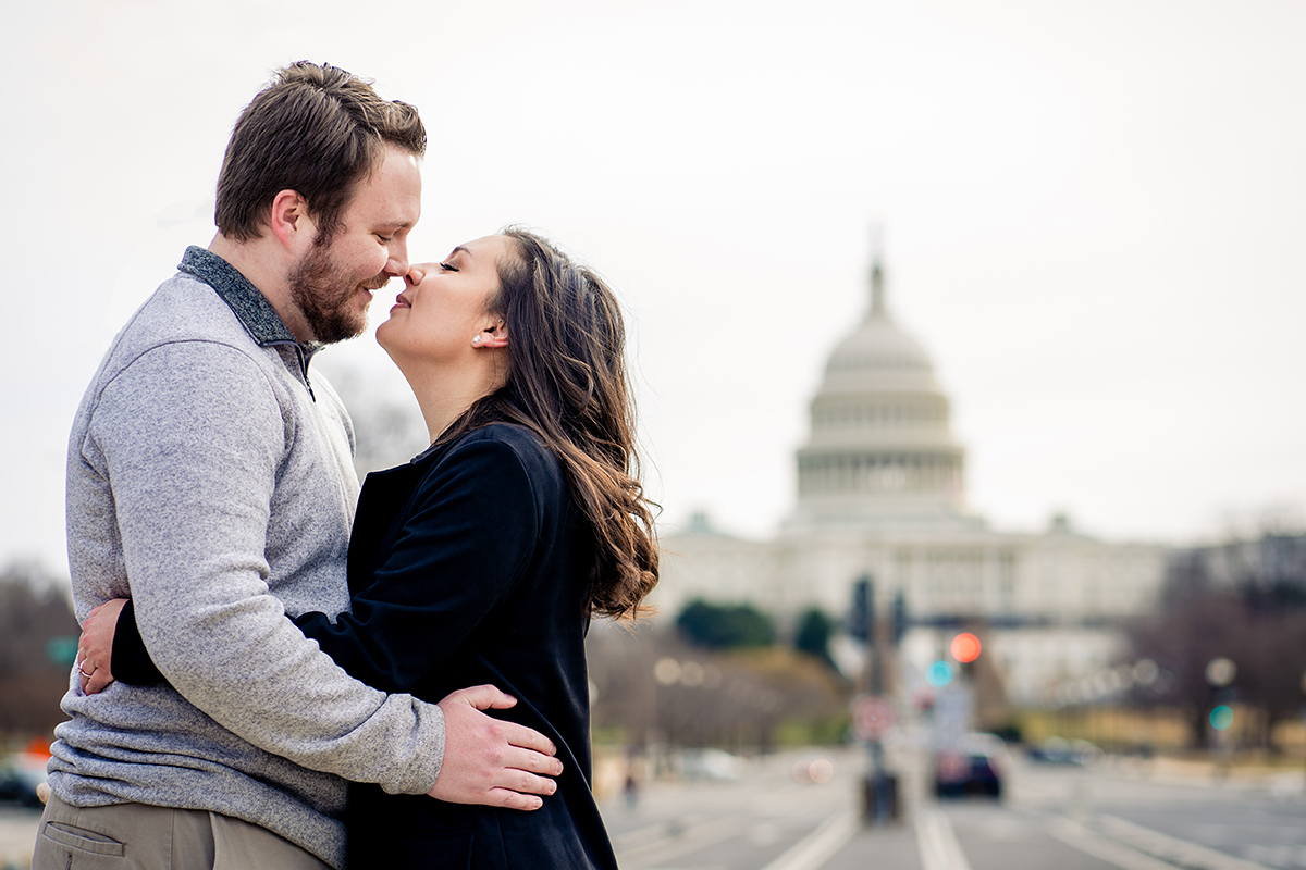 Couple posing for Freedom Plaza winter engagement session with a view of the Capitol Building in DC by Potok's World Photography